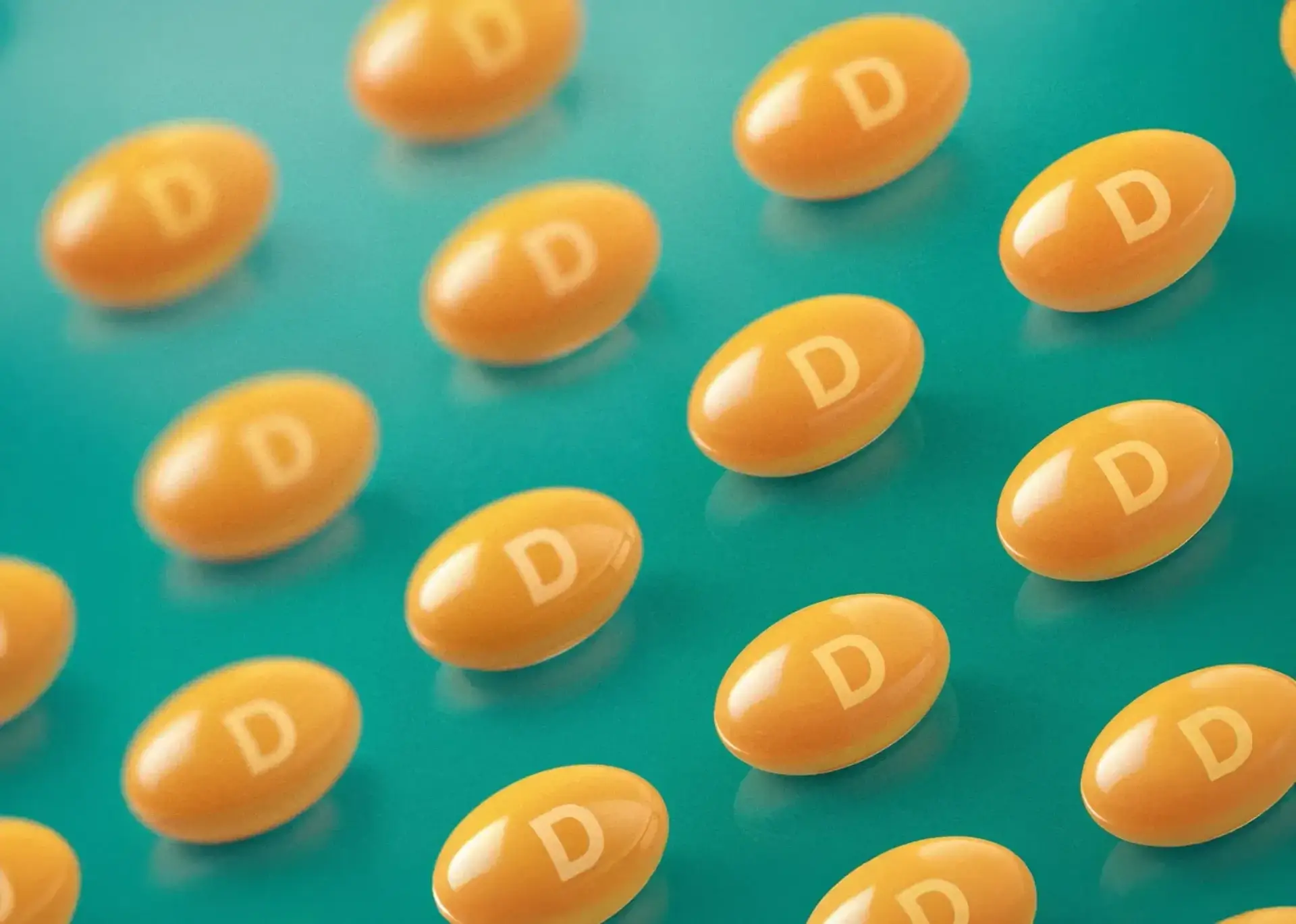 Orange capsules with the letter "D" scattered on a teal surface.